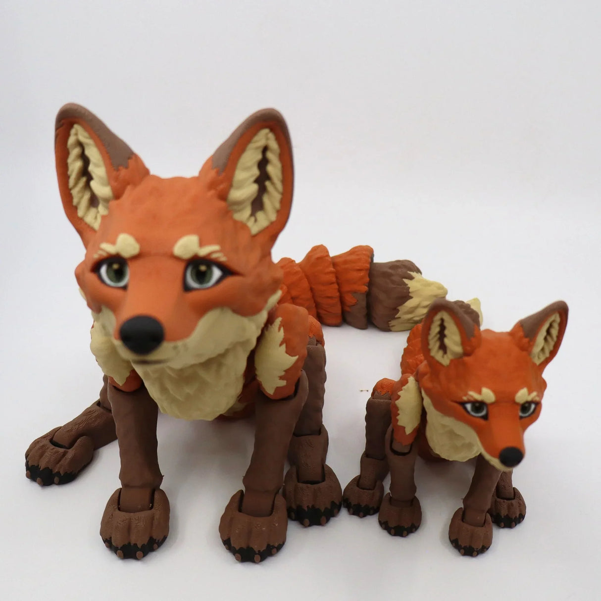 Two 3D printed sensory fox toys with jointed limbs in orange and brown on a white background