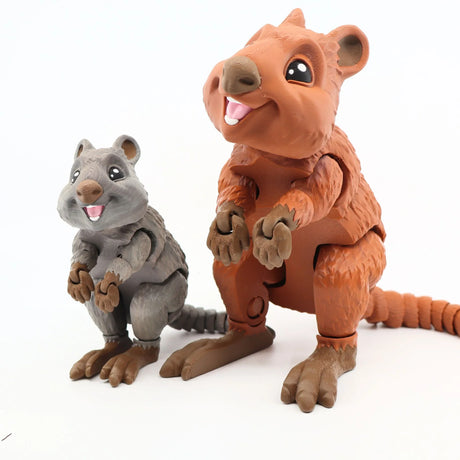 Two colorful 3D printed quokka sensory toys, one gray and one brown, with smiling faces