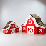 Two colorful 3D printed red barn sensory toys with white details on a plain background.