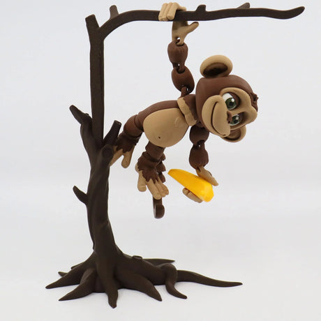 3D printed sensory monkey toy hanging from tree branch, holding yellow banana, educational tool