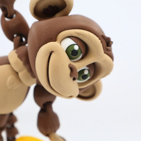 3D printed monkey sensory toy with movable limbs and green eyes on a white background