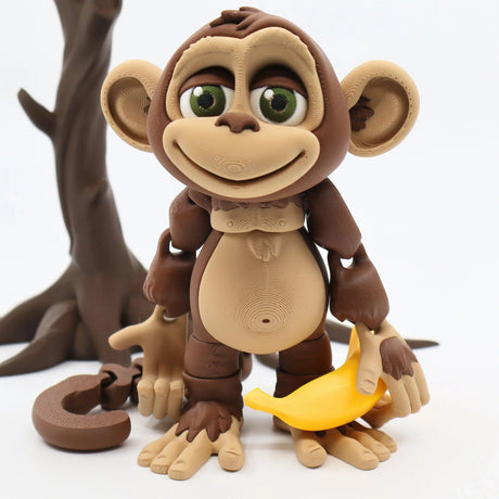 3D printed sensory monkey toy holding a yellow banana, standing in front of a tree