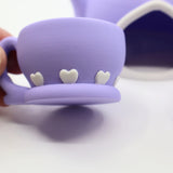 Purple 3D printed sensory toy teacup with white heart details on a white background