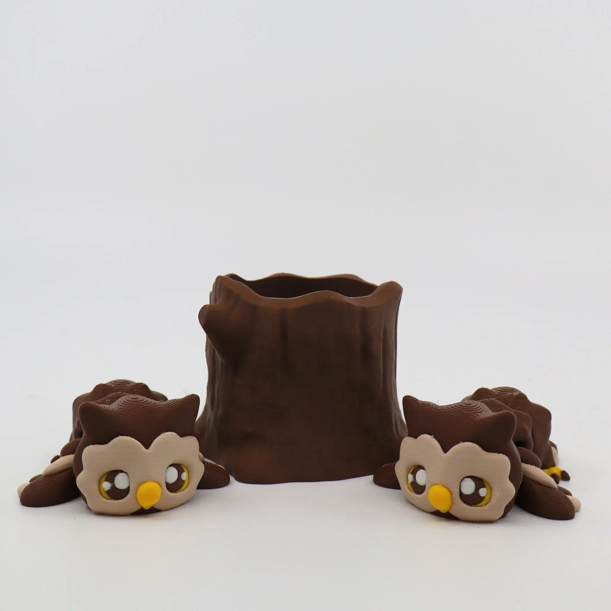 3D printed sensory toy set with two brown owls and a tree stump on white background