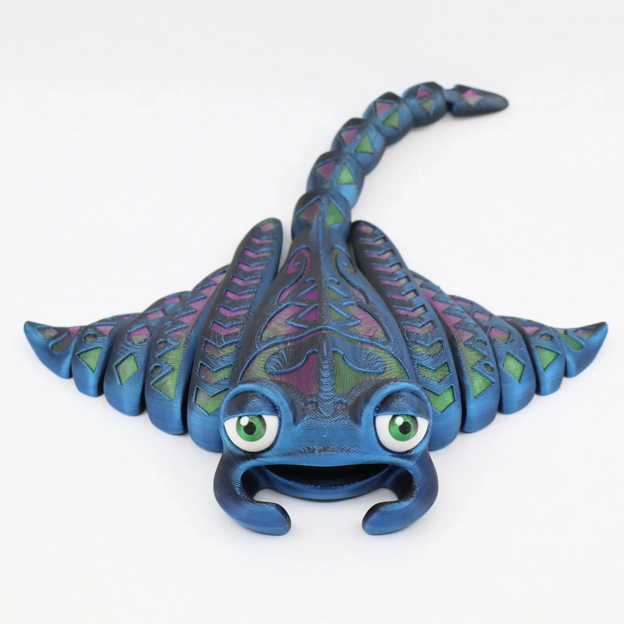 Colorful 3D printed ray-shaped sensory toy with green eyes and detailed patterns on wings.