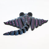 Colorful 3D printed sensory stingray fidget toy with articulated tail on white background