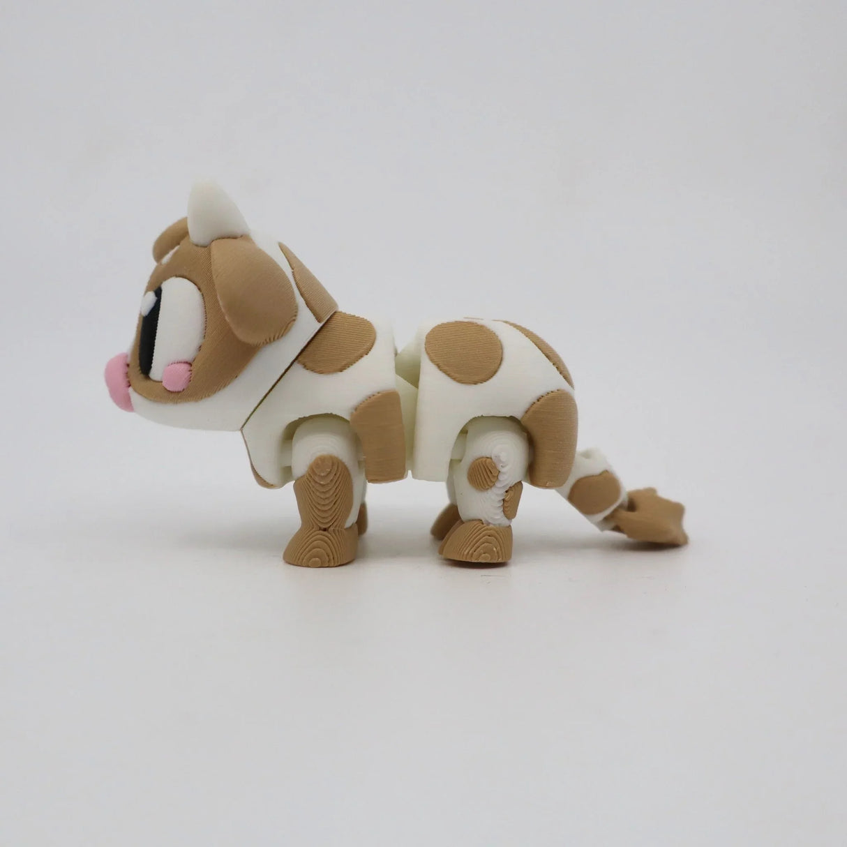 3D printed sensory toy cow with brown spots and big eyes on a plain background