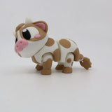 3D printed sensory toy cow with brown spots and pink nose on white background