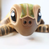 Close-up of a colorful 3D printed sea turtle sensory toy with big eyes on a white background.