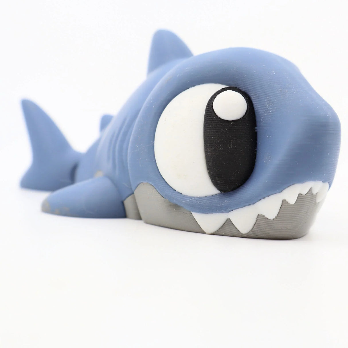 3D printed blue shark sensory toy with large eyes and white teeth on a white background