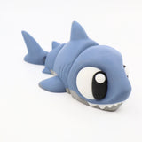 Blue 3D printed shark sensory toy with large eyes on a white background