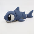 Blue 3D printed sensory shark toy with large eyes on white background