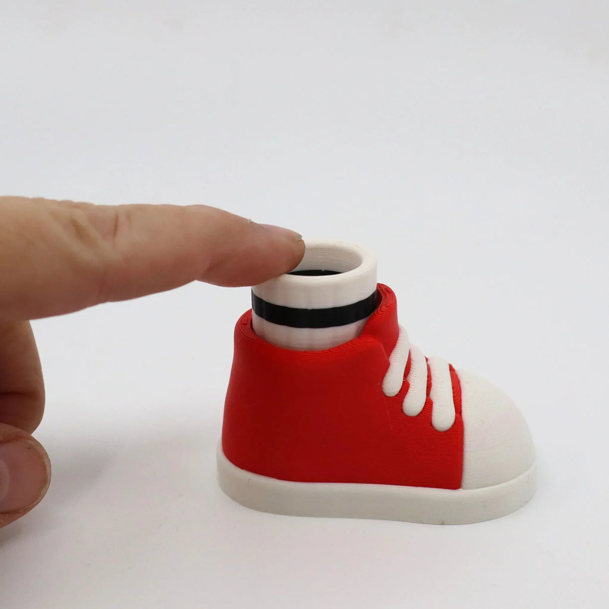 Red and white 3D printed sneaker fidget toy with finger pressing top, sensory tool for kids