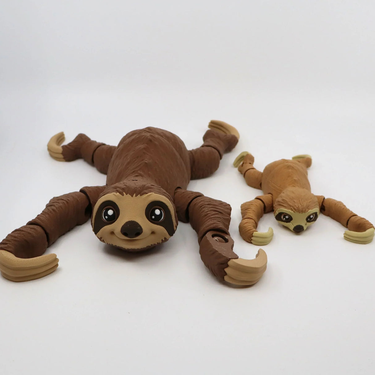 Two 3D printed flexible sloth sensory toys with jointed limbs on a white background.
