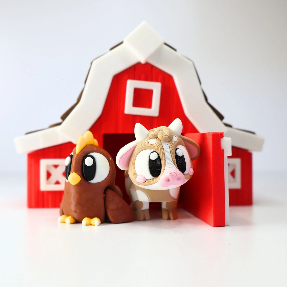 Cute 3D printed cow and chicken sensory toys in front of a red toy barn