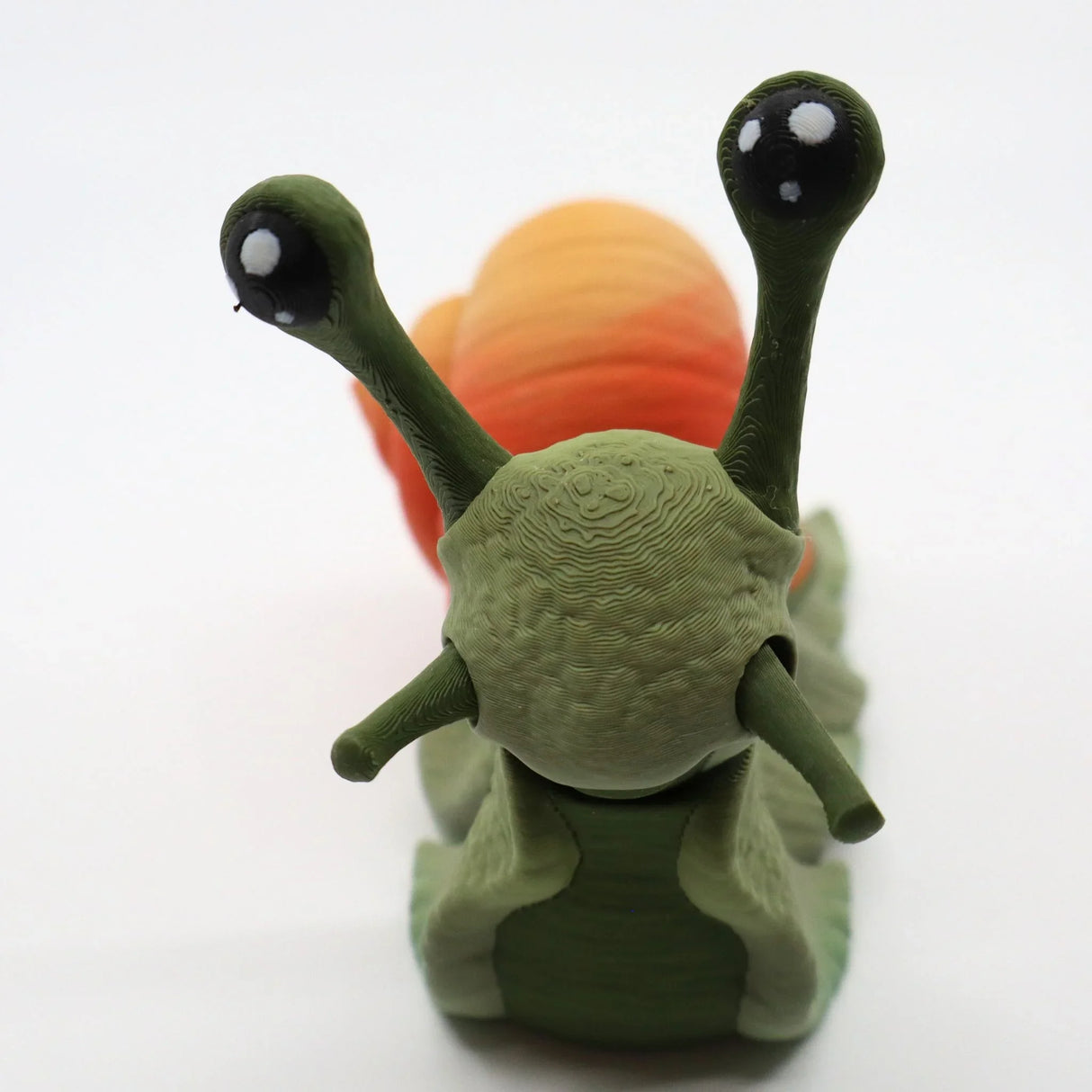 3D printed sensory snail toy with green body and orange shell on white background