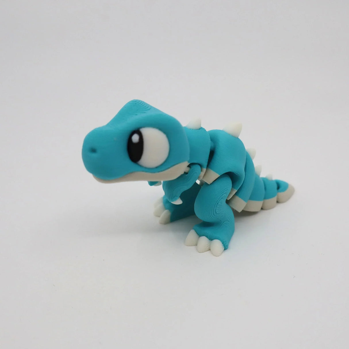 Blue 3D printed dinosaur sensory toy with white spikes on plain background