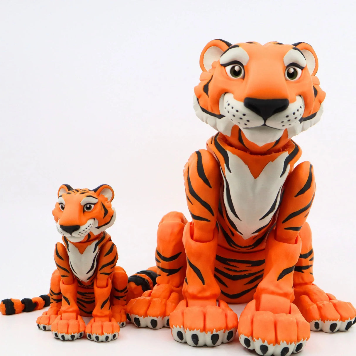 Two orange 3D printed sensory tiger toys with black stripes and white details on white background