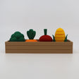 3D printed sensory toy vegetables in a brown tray, including broccoli, carrot, beet, and corn