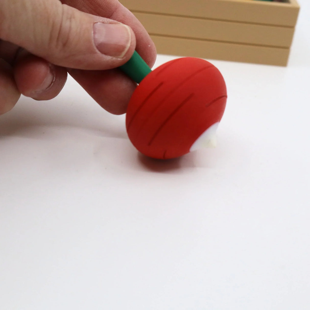Hand holding a red veggie-shaped 3D printed sensory fidget toy on a white surface