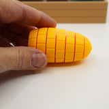 Hand holding a yellow 3D printed corn-shaped sensory fidget toy on a white surface.