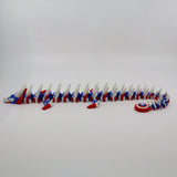 Red, white, and blue 3D printed flexi dragon toy with star pattern and shield, ideal for sensory play