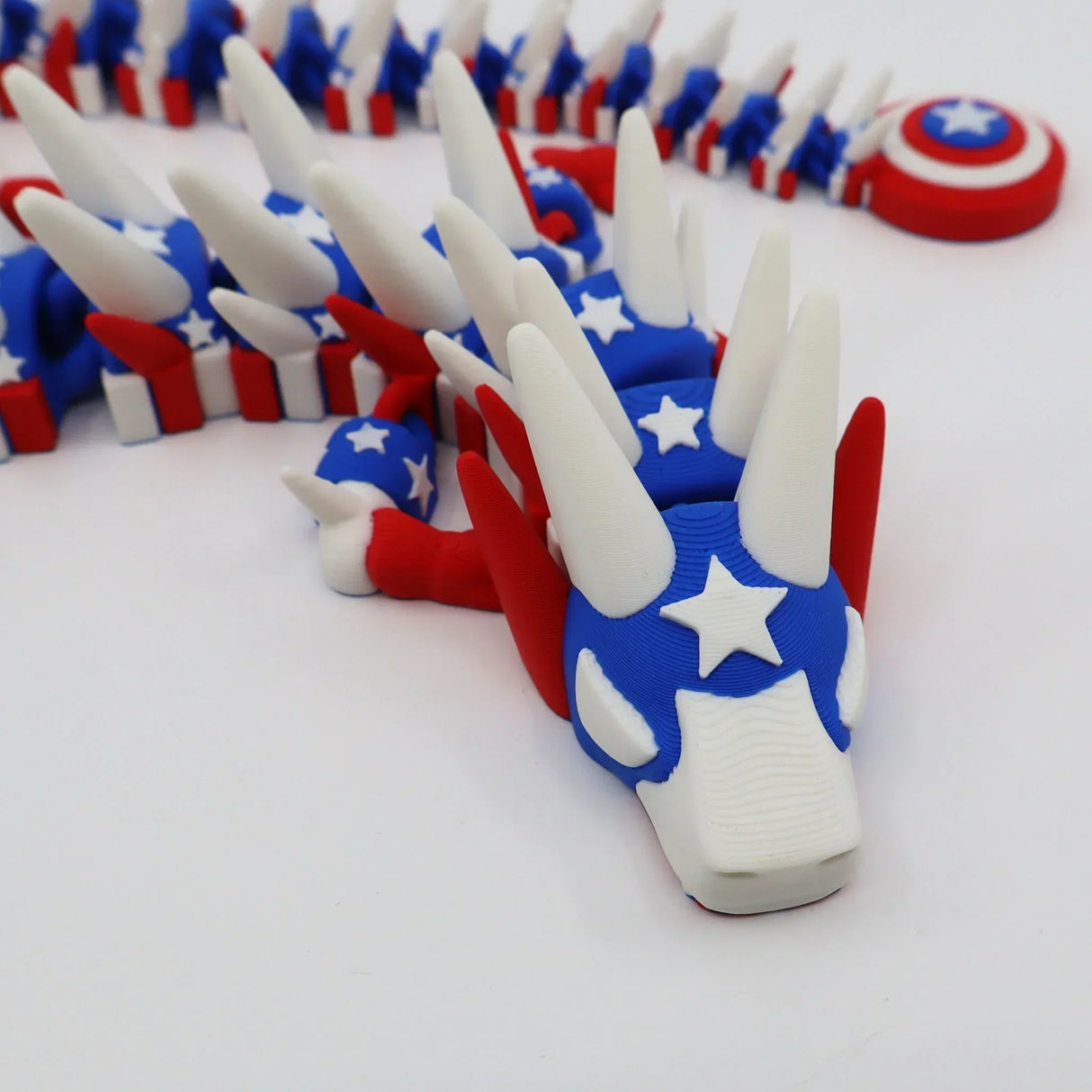 3D printed patriotic flexi dragon fidget toy with stars, stripes, and shield for sensory play