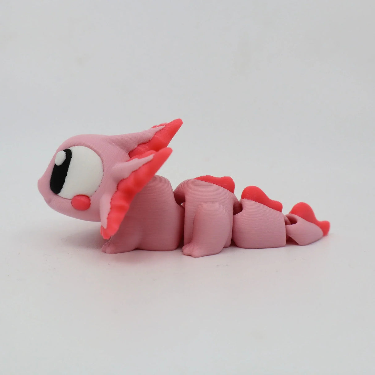 Pink 3D printed axolotl sensory toy with segmented body and large eyes on white background