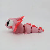 Pink 3D printed axolotl sensory toy with segmented body and large eyes on white background