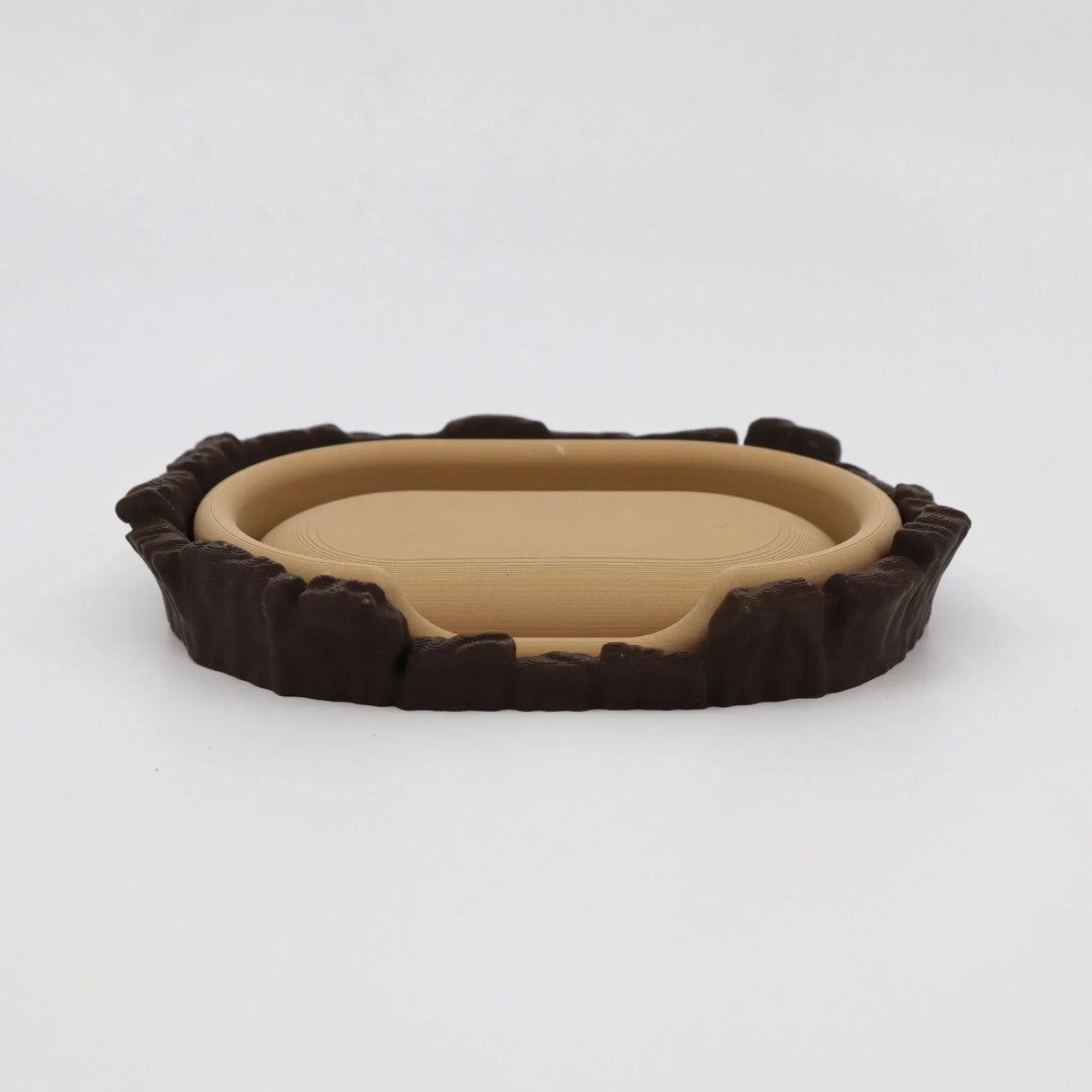 3D printed sensory toy resembling a miniature brown and beige animal bed with textured edges.