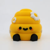 Yellow 3D printed fidget toy with daisy flowers, cute smile, and black feet for sensory play