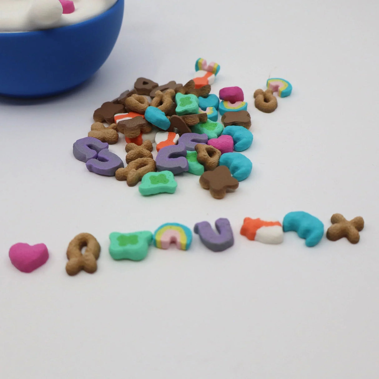 Colorful sensory toy cereal pieces spilled from a blue bowl on a white surface