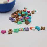 Colorful sensory toy cereal pieces spilled from a blue bowl on a white surface