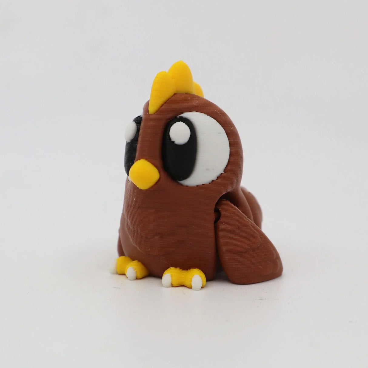 Cute 3D printed brown chicken sensory toy with big eyes and yellow beak on white background