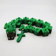 Pixelated green dragon fidget toy with blocky segments and sword, 3D printed sensory tool for kids