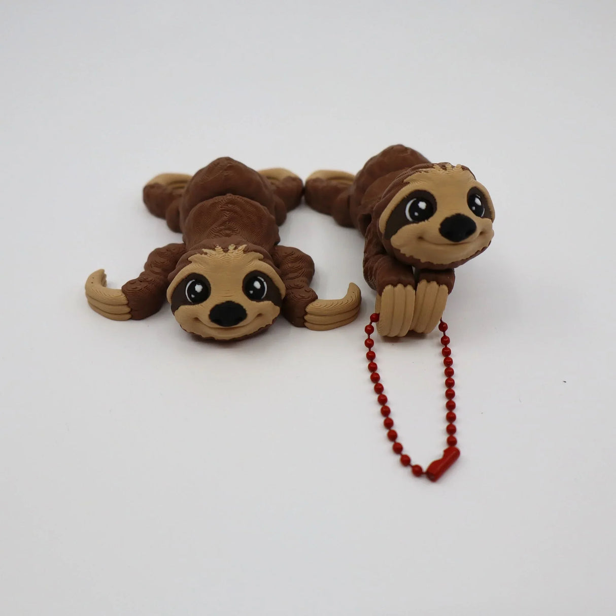 Two brown 3D printed sloth sensory fidget toys on white background, one with red bead chain.