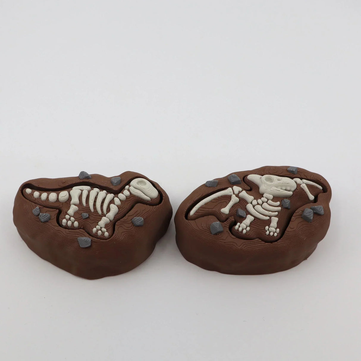 3D printed dinosaur fossil sensory toys with detailed bones and textured earth