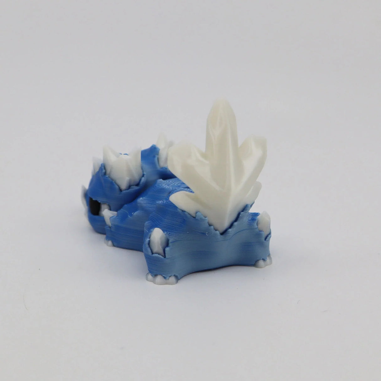 Blue and white 3D printed sensory dinosaur toy with crystal-like spikes on a white background.