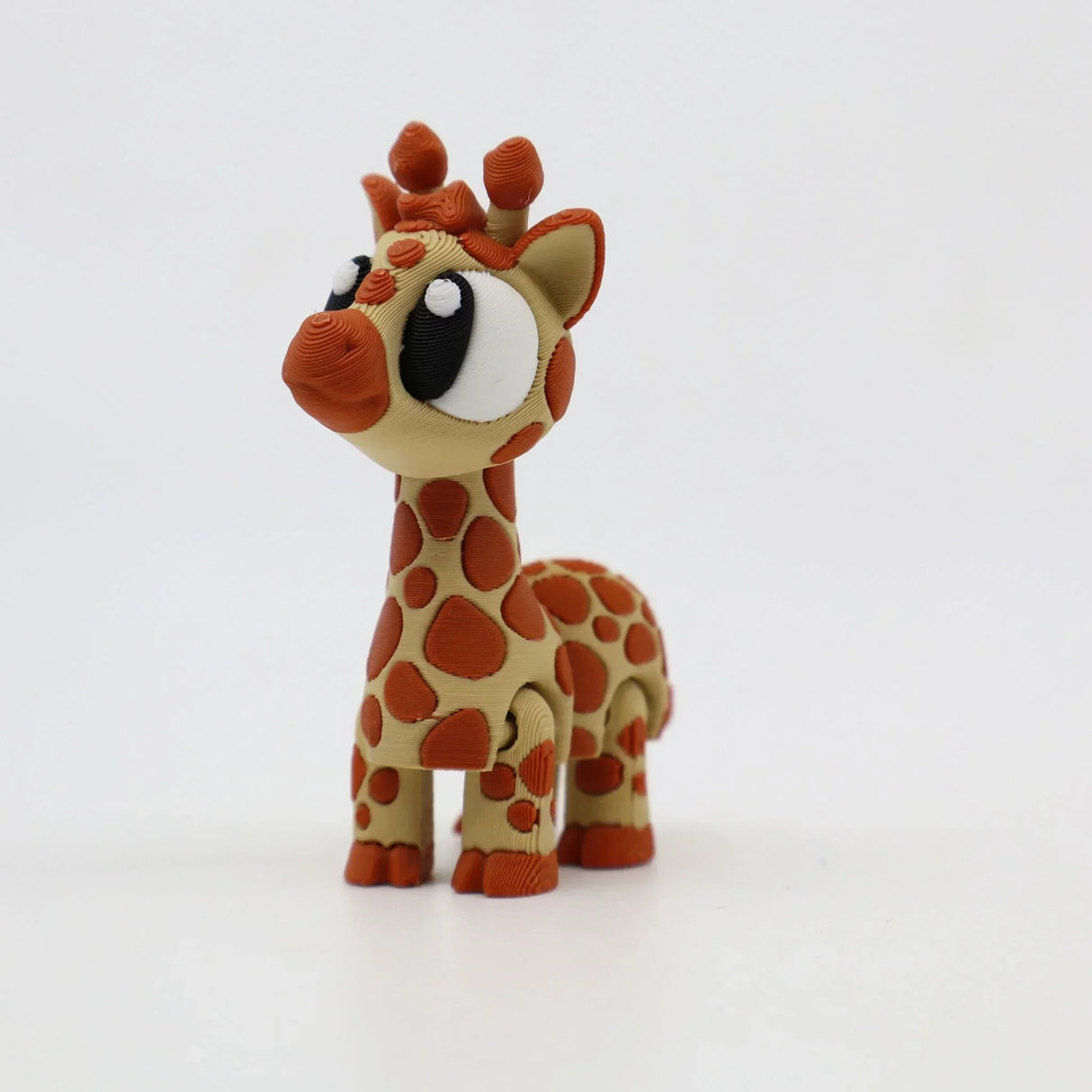 3D printed sensory giraffe toy with large eyes and orange spots on white background
