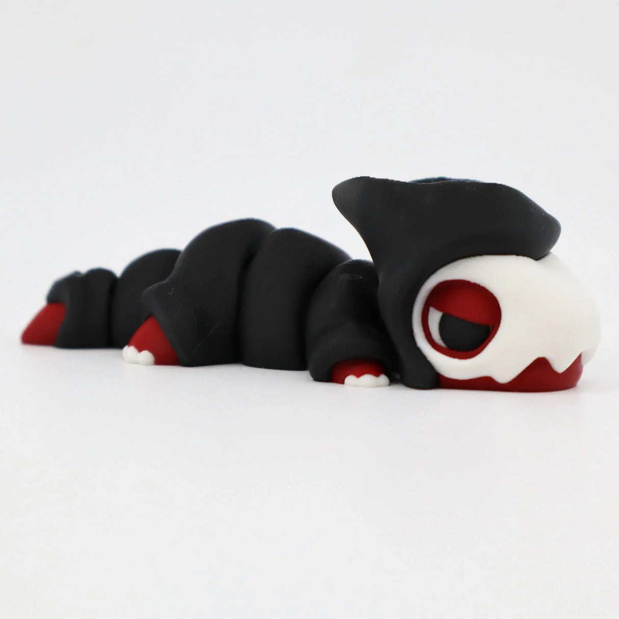 3D printed black and red sensory toy caterpillar with a white skull head on white background