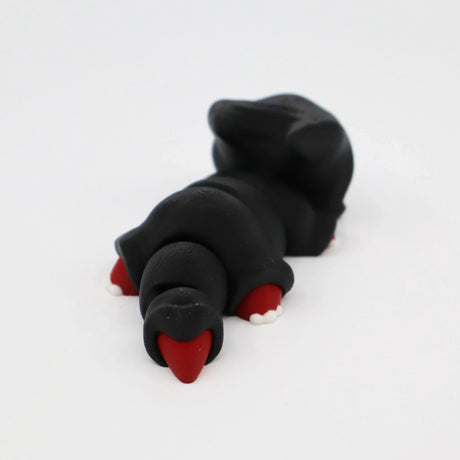 3D printed black sensory toy mole with red nose and claws on white background