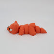 Orange 3D printed segmented sensory toy cat lying on white background