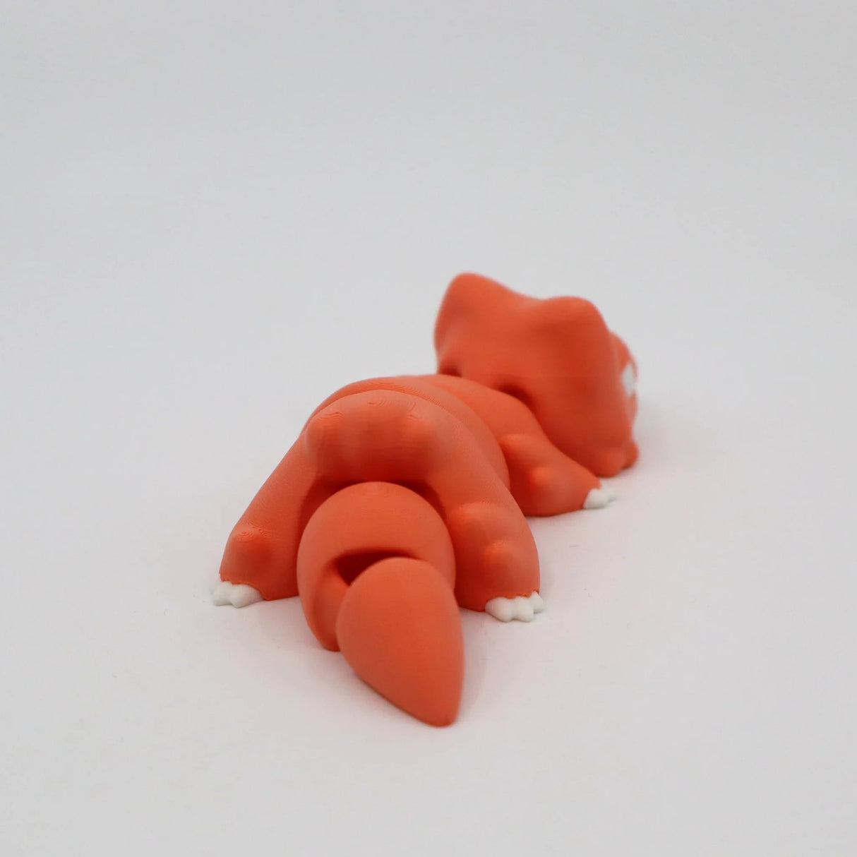 Orange 3D printed sensory toy fox lying down on white background