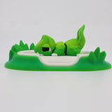 Green 3D printed sleeping animal sensory toy on a meadow-themed base with grass details