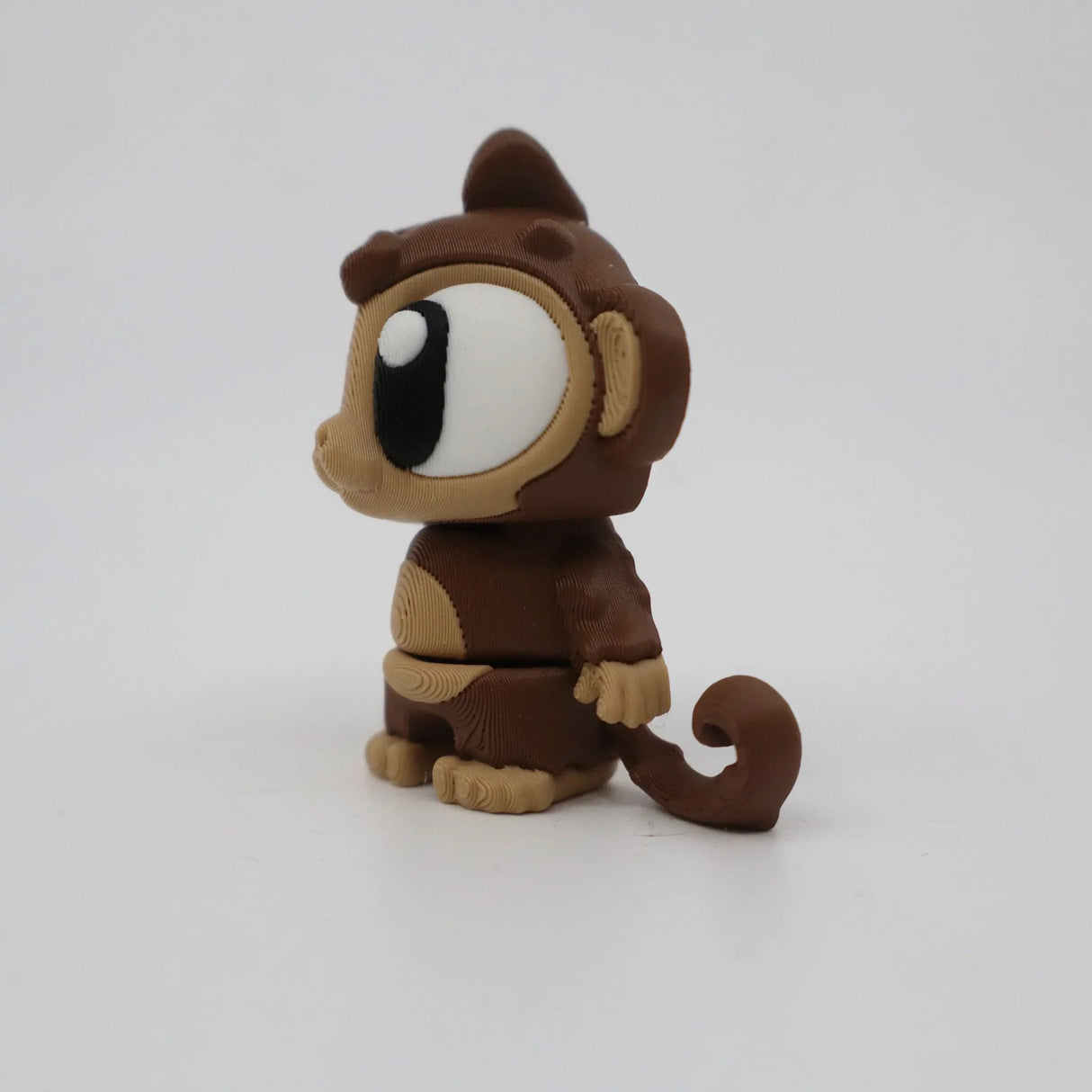 3D printed brown monkey sensory toy with large eyes on a white background