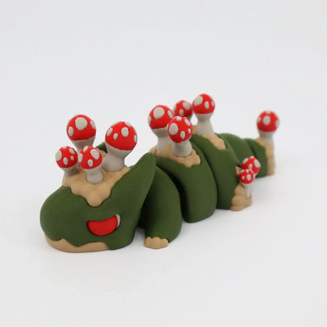 3D printed green caterpillar toy with red and white mushrooms on its back on white background
