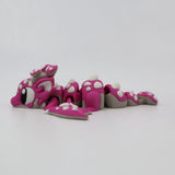 Pink 3D printed flexi dragon fidget toy with white spots, designed for sensory play and tactile stimulation.