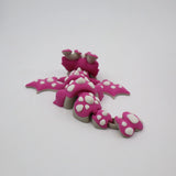 Pink 3D printed flexi dragon fidget toy with white spikes, designed for sensory play and tactile stimulation.