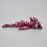 Pink 3D printed flexi dragon fidget toy with white spots, designed for sensory play and tactile stimulation