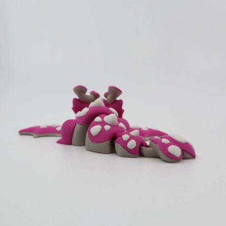 Pink 3D printed flexi dinosaur toy with white spikes, sensory fidget for kids